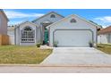 Charming single-Gathering home features a teal front door, well-maintained lawn, and an attached two-car garage at 142 Ethan Ave, Davenport, FL 33897