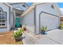 Close-up of home exterior with teal front door, landscaping, and a two-car garage at 142 Ethan Ave, Davenport, FL 33897
