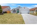 Charming single-Gathering home features a teal front door, well-maintained lawn, and an attached two-car garage at 142 Ethan Ave, Davenport, FL 33897