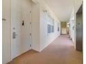 Hallway with white walls and carpet leading to a unit door at 1501 Northern Harrier Way # 202, Reunion, FL 34747
