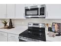 Close up of the stainless steel range and microwave in the modern well lit kitchen at 157 Waterstone Loop, Tavares, FL 32778