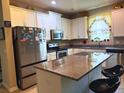 A well-lit kitchen features an island with a granite countertop, stainless steel appliances, and white cabinetry at 3333 Sagebrush St, Harmony, FL 34773