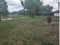Expansive backyard view with a large pond, partial fence and a vintage barrel for burning at 4345 Old Colony Rd, Mulberry, FL 33860