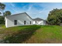 A view of the green backyard of a white home, showcasing the ample space for outdoor activities at 6479 Apple St, St Cloud, FL 34771