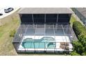 Aerial view of the screened-in pool area, featuring a geometric pool design and patio furniture at 805 Suffolk Pl, Davenport, FL 33896