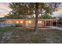 Single-story home features a cozy porch, warm lighting, and an inviting front yard shaded by mature trees at 807 E Airport Blvd, Sanford, FL 32773