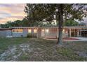Single-story home features a cozy porch, warm lighting, and an inviting front yard shaded by mature trees at 807 E Airport Blvd, Sanford, FL 32773