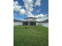 Expansive backyard featuring a screened-in patio and verdant lawn enclosed by a white privacy fence at 12372 Stone Bark Trl, Orlando, FL 32824