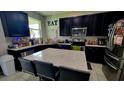 Modern kitchen featuring black cabinetry, stainless steel appliances, and a large island with seating at 12372 Stone Bark Trl, Orlando, FL 32824
