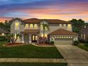 Beautiful two-story home at sunset featuring a well-manicured lawn and a two-car garage and landscaping at 13130 Meergate Cir, Orlando, FL 32837