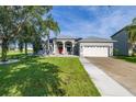 Inviting single-story home with a lush green lawn, mature trees, and a driveway leading to the garage at 1760 Boat Launch Rd, Kissimmee, FL 34746