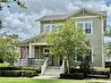 Attractive two-story house with a quaint front porch, manicured shrubs, and a beautiful American flag at 1801 Coastal Ct, Celebration, FL 34747