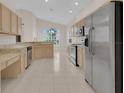 Well-lit kitchen features light wood cabinets, stainless steel appliances, tile flooring and a large window at 231 Lewis Dr, Davenport, FL 33837