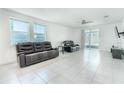 Bright living room with tile flooring, large windows, ceiling fan, and plush leather seating at 3442 Monaco Ln, Davenport, FL 33897
