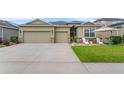 Inviting home exterior with a well-manicured lawn, stone accents, a two-car garage, and a charming front patio at 3698 Cortland Dr, Davenport, FL 33837