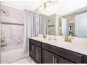 Bright bathroom featuring a double sink vanity, tub with shower, and marble tile surround at 4903 Windermere Ave, Kissimmee, FL 34746