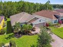Beautiful home featuring a paver driveway, lush landscaping, and verdant lawn, set amongst mature trees and a lake at 582 San Joaquin Rd, Kissimmee, FL 34759