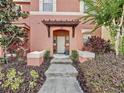 Welcoming front entrance to townhome #109 featuring a covered pergola and mature plants at 109 Pompano Beach Dr, Kissimmee, FL 34746