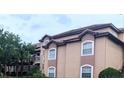 Exterior of condo building with tan siding, white trim and a red tile roof at 13838 Fairway Island Dr # 1418, Orlando, FL 32837