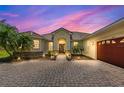 Single-story home exterior at dusk featuring a brick driveway, manicured landscaping, and attached garage at 3427 Harborside Ct, Kissimmee, FL 34746