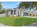 Landscaped front yard leads to a charming single-Gathering home with a gray roof and a two-car garage at 4903 Santa Clara Dr, Orlando, FL 32837