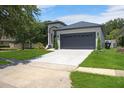 Front exterior of home showcasing a gray roof, a two-car garage, and a green lawn at 4903 Santa Clara Dr, Orlando, FL 32837