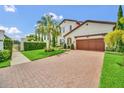 Beautifully landscaped home featuring a brick driveway, lush lawn, and an attached two car garage at 10836 Royal Cypress Way, Orlando, FL 32836