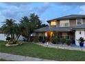 Landscaped front yard with palm trees leading to a charming two-story home at 11922 Ottawa Ave, Orlando, FL 32837