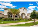 Attractive home exterior with arched entry, stone details, beautiful landscaping, and a paver driveway at 13809 Abberwick Dr, Orlando, FL 32832