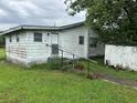 Front exterior view of a modest white home with aged features and green lawn at 1886 Pleasant Hill Rd, Kissimmee, FL 34746