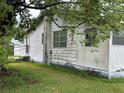 Side view of a white home with visible wear and overgrown foliage at 1886 Pleasant Hill Rd, Kissimmee, FL 34746
