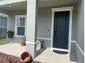 Inviting covered front porch with a dark blue door, potted plants, and stylish decor accents at 1896 Basenji Dr, Lake Alfred, FL 33850