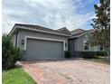 This home features a brick driveway, a gray two-car garage door, and attractive landscaping at 2016 Lakeside Ave, Davenport, FL 33837