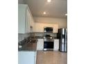 Updated kitchen featuring white cabinets, stainless steel appliances, granite countertops, and tile flooring at 254 Mandovi St, Davenport, FL 33837