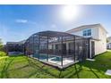 Screened-in pool with a sunny green lawn, perfect for outdoor enjoyment and relaxation at 2623 Calistoga Ave, Kissimmee, FL 34741