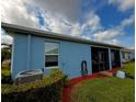 Rear exterior view showing blue siding, screened-in lanai, and lush landscaping at 2919 Woodward Ln, Winter Haven, FL 33884