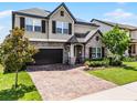Charming two-story home with a brick driveway, stone accents, lush landscaping, and a two-car garage at 3420 Middlebrook Pl, Harmony, FL 34773