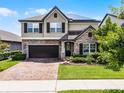 Charming two-story home with a brick driveway, stone accents, lush landscaping, and a two-car garage at 3420 Middlebrook Pl, Harmony, FL 34773
