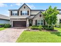 Charming two-story home with a brick driveway, stone accents, lush landscaping, and a two-car garage at 3420 Middlebrook Pl, Harmony, FL 34773