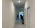 View down long hallway leading to living spaces with tile flooring and neutral paint at 3476 Yarian Dr, Haines City, FL 33844