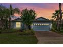Charming single-story home featuring a brick driveway, manicured lawn, and lush tropical landscaping under a colorful twilight sky at 3606 Solana Cir, Clermont, FL 34711