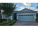 Charming single-story blue home with a brick driveway, attached garage, and manicured landscaping at 3606 Solana Cir, Clermont, FL 34711