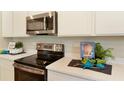 Close-up of modern kitchen featuring stainless steel appliances, quartz countertops, and stylish cookbook display at 5216 Bee Balm St, Lake Hamilton, FL 33851