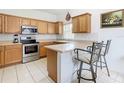 Well-lit kitchen with stainless steel appliances, wood cabinets, breakfast bar and sleek backsplash at 572 Sienna Dr, Poinciana, FL 34759