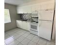 Bright kitchen with white cabinets, appliances, backsplash and tiled floor at 702 Michigan Ct # 4, St Cloud, FL 34769