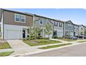 Colorful townhouses with manicured lawns and attached garages sit on a well-maintained street at 955 Grandin St, Davenport, FL 33837