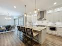 Modern kitchen with stainless steel appliances, a marble island with barstool seating, and hardwood floors throughout at 960 Civitas Way, Winter Garden, FL 34787