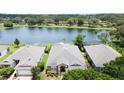 Aerial view of the property featuring views of the water, manicured lawn, and tidy landscape beds at 9824 Secret Cove Ln, Orlando, FL 32832