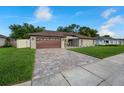 Inviting single-story home with a brick driveway, lush grass and well-maintained landscaping at 12542 Idaho Woods Ln, Orlando, FL 32824