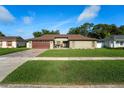 Well-maintained single-story home with a brick driveway, two-car garage, and manicured lawn at 12542 Idaho Woods Ln, Orlando, FL 32824